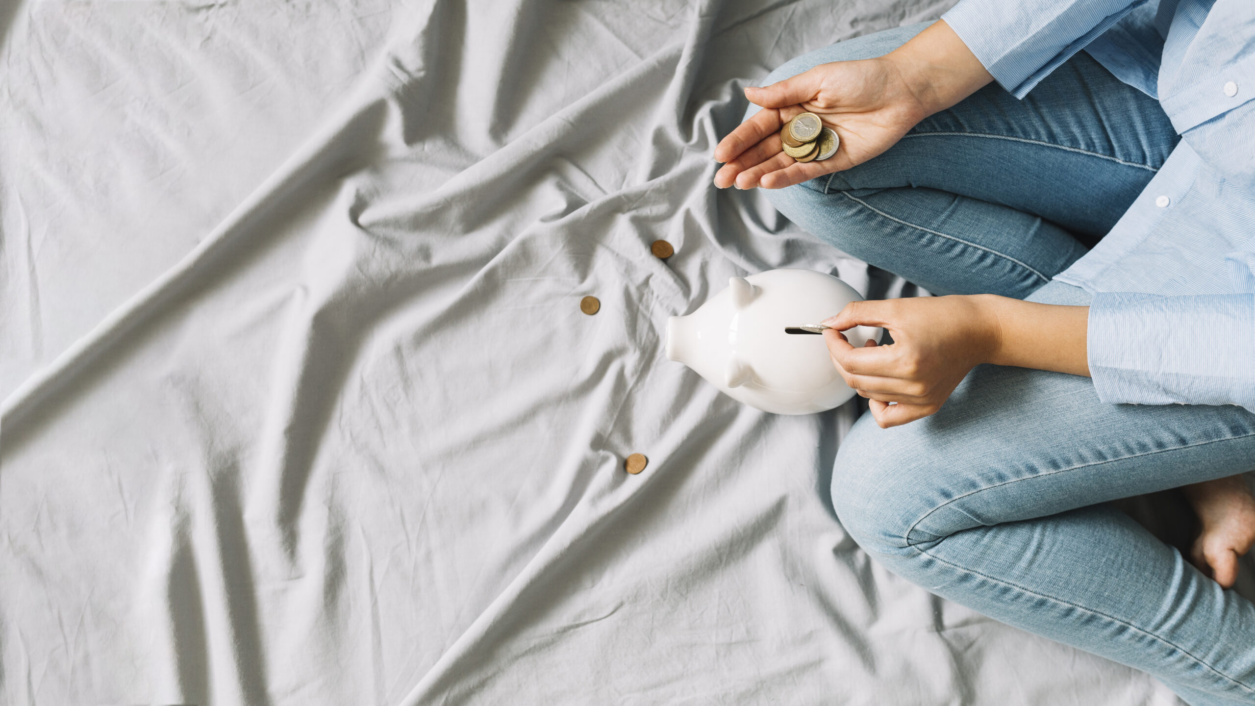 elevated-view-person-s-hand-inserting-coins-piggybank